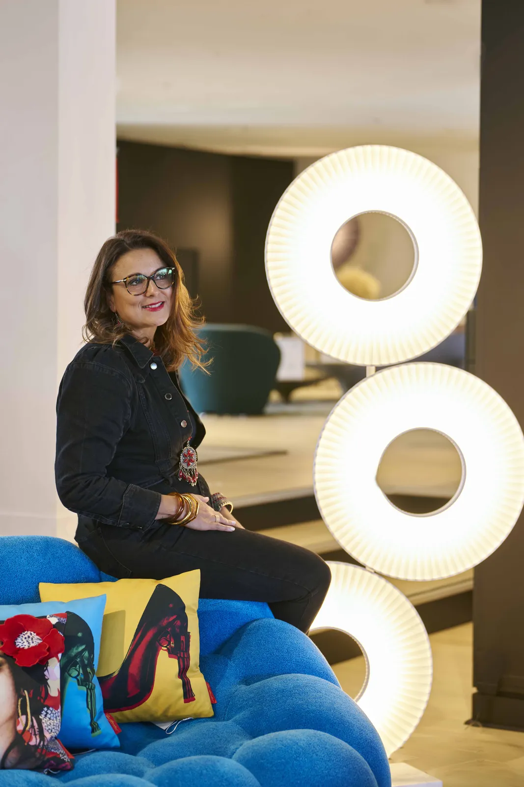 Linda Dubuisson en showroom, assise face à des luminaires design